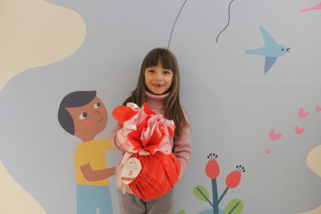 Bambina con cardiopatia congenita con in mano panettone di Natale solidale