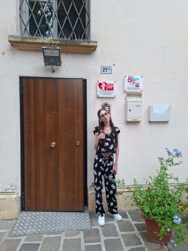 Romina davanti alla porta del Polo dei Cuori, casa di accoglienza di Piccoli Grandi Cuori